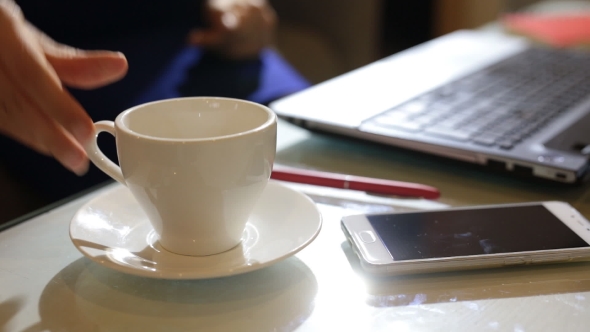 Beautiful Young Woman Is Seating Indoors At a Cafe Restaurant, Holding a Coffee Cup