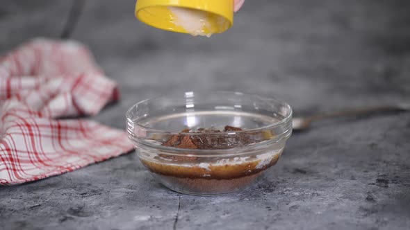 Female Adding Melted Butter To Crushed Biscuits To Make Pastry Crust for Cheesecake