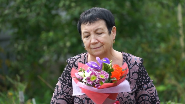 Footage Elderly Woman Holding a Bouquet Of Flowers Outdoors.