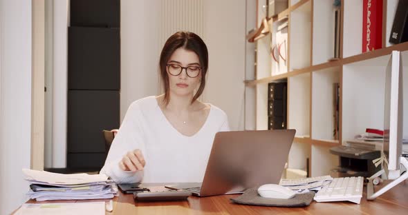 Beautiful Young Woman in Glasses Works on Laptop Computer While on Office