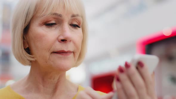 Closeup Focused Serious Caucasian Elderly Woman Holding Smartphone Looking at Phone Screen Typing