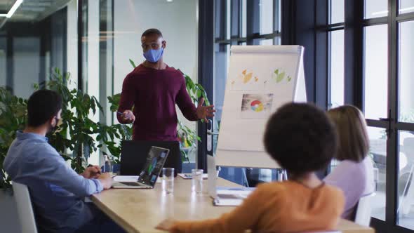 Diverse business people wearing masks sitting listening to a presentation in office