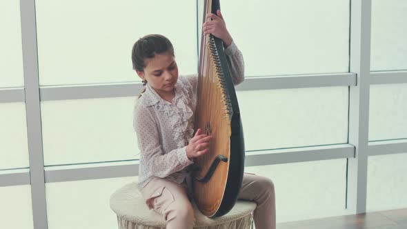 A Teenage Girl Bandura Player Performs a Piece of Music on the Bandura