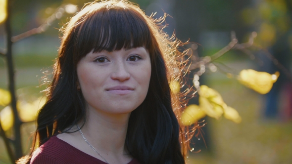 Portrait Of Young Pregnant Woman In Red Dress Looking At Camera In The Autumn Park At Sunset