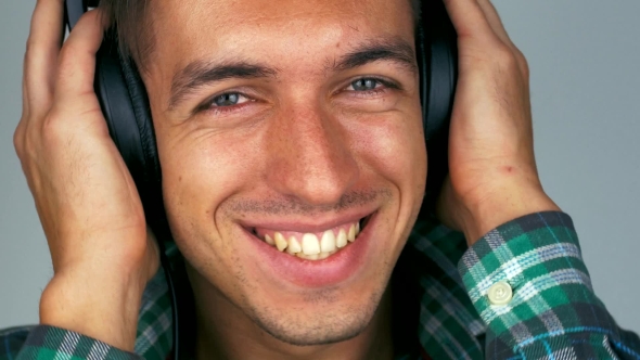Man Smiles and Listens to Music on Headphones