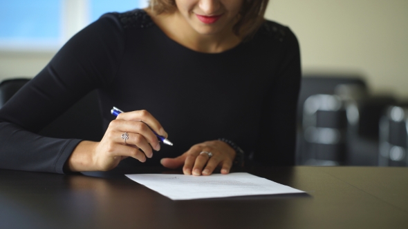 Woman's Hand With Pen Signing Document,