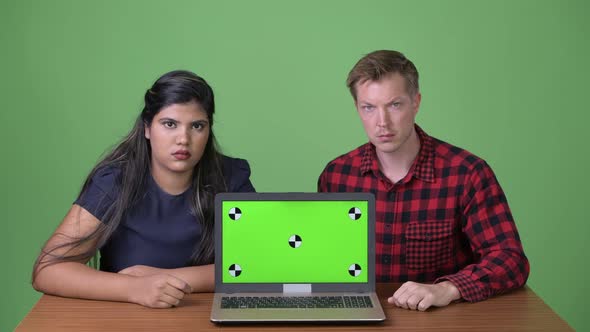Young Multi-ethnic Business Couple Together Against Green Background