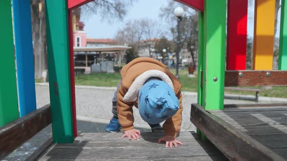 A Boy on a Playground in an Autumn Park Climbs a Hill in Cloudy Weather