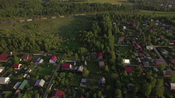 Flying Over Village Houses and Moving Cargo Train alt