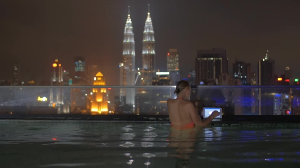 Woman With Pad On Rooftop Pool In Kuala Lumpur, Malaysia