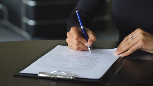 Woman's Hand With Pen Signing Document