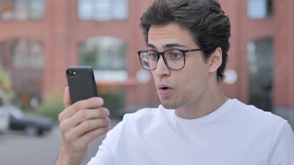 Young Man Surprised by Results on Smartphone