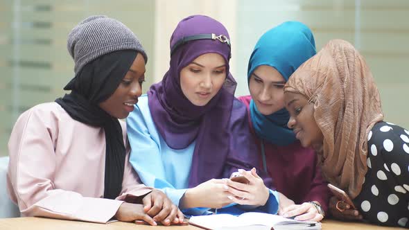 Portrait of Elegantly Dressed Muslim Girls Looking at the Hands of One of Her Friends