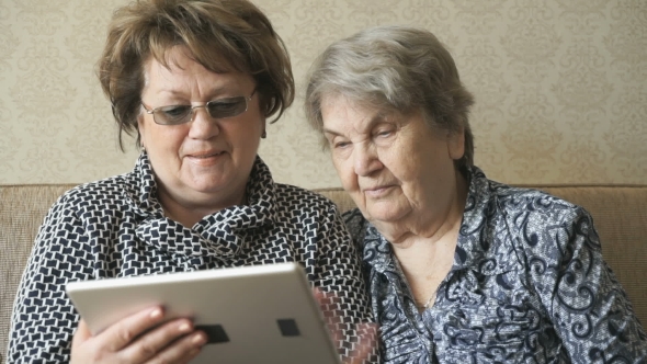 Two Women Watching Photos On a Digital Tablet