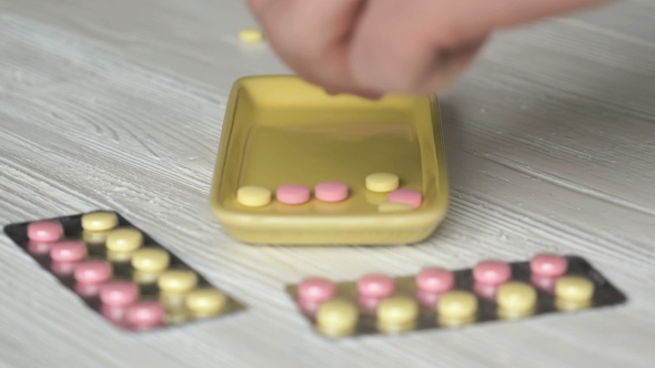 Hand Collects The Tablets In a Yellow Container