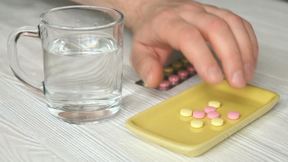 Man's Hand Takes The Tablets From The Container