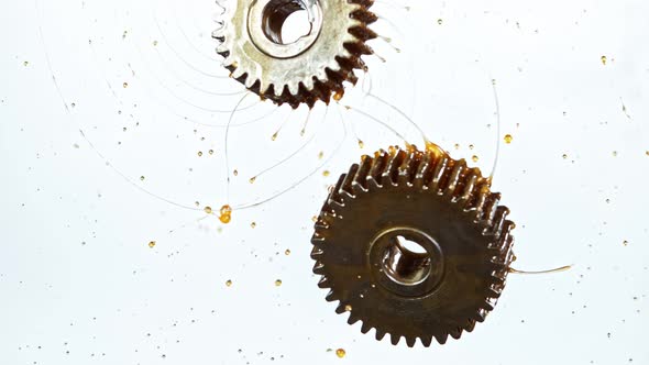 Super Slow Motion Shot of Rotating and Splashing Metal Cogwheels on White Background at 1000 Fps