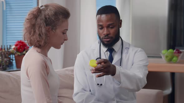 AfricanAmerican Ethnicity Doctor Giving Medication to Sick Young Woman During Home Visit