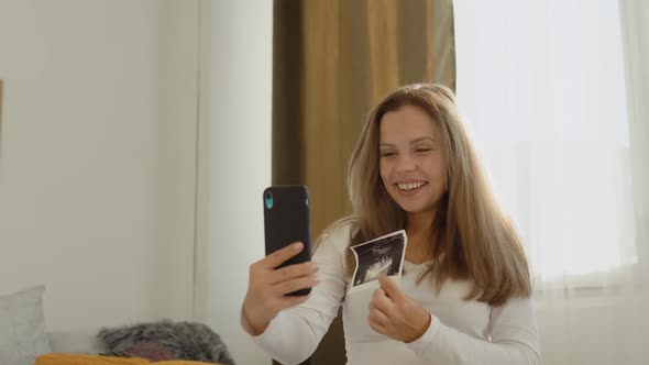 Pregnant Woman Shows the Interlocutor a Photo From the Ultrasound Examination of the Fetus Using a