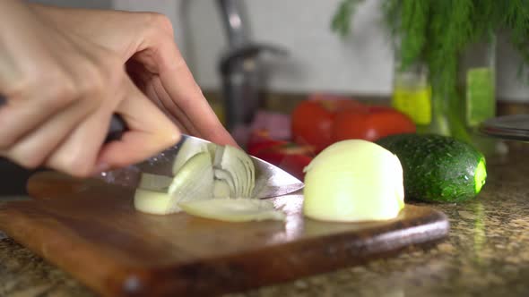 Female housewife prepares healthy food in kitchen. She cuts vegetables,