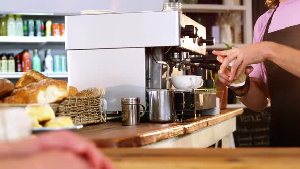 Waiter serving coffee to customer at counter