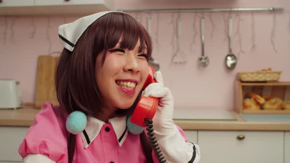 Portrait of Joyful Charming Asian Female Cosplayer Talking on Landline Phone