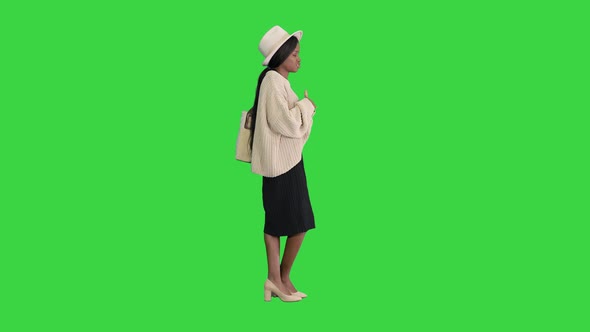 Young African American Woman in Knitwear and White Hat Talking and Gesturing on a Green Screen