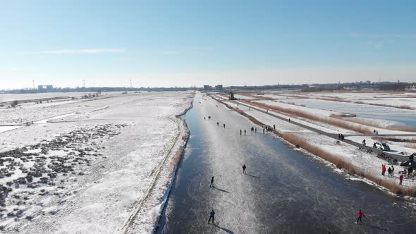 People ice skating on frozen canal, iconic Netherlands winter scene, aerial view