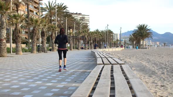 Woman in Sportswear Running Along the Beach