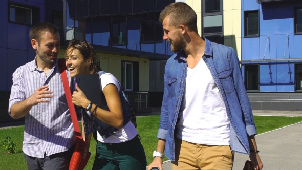 Group Of Students Walking Together Outside In Urban Area. Three Caucasian Men And Women Walking At a