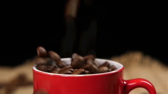 Coffee Beans Falling Into Red Small Cup. Slow Motion