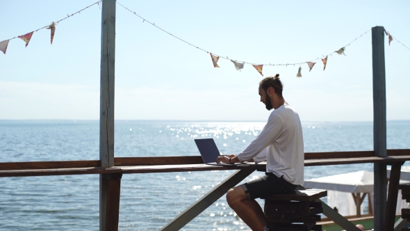 Man Uses Laptop On Background Of Sea