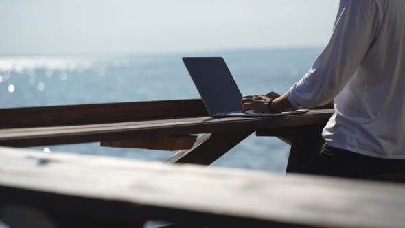 Young Businessman Using His Laptop On The Waterfront On Sea Background