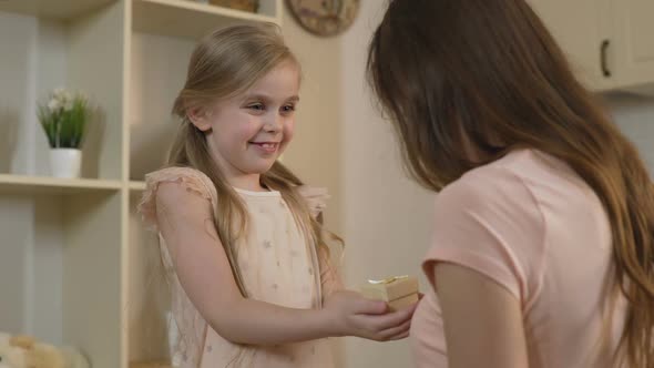 Loving Daughter Presenting Birthday Gift to Mother, Tender Surprise From Child