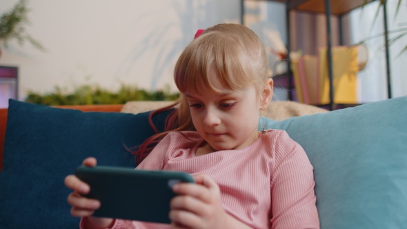 Worried Teen Child Girl Kid Enthusiastically Playing Racing Video Online Games on Smartphone at Home