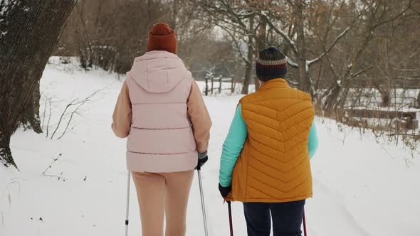 Women Practice Nordic Walking with Trekking Poles at Winter