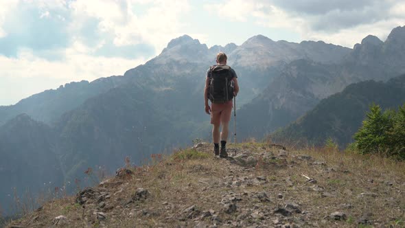 Man Hiker Tourist Walking on Edge of the Mountain and Looks Into the Distance