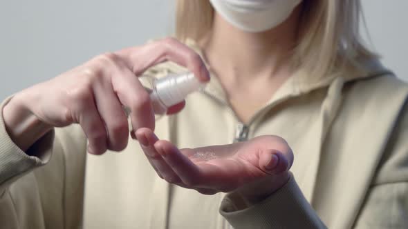 Blonde woman in protective mask with disinfection gel