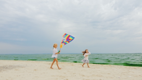 Two Children Playing With a Kite On The Beach On Sea And Sky Background