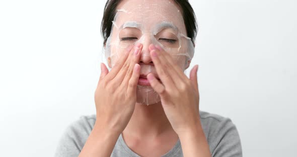 Woman apply paper mask sheet on face 