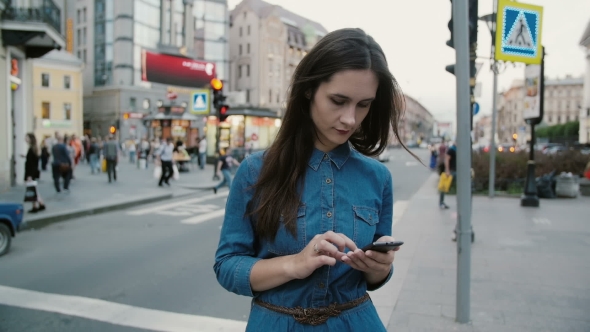Pretty Woman in a Busy Street. Young Woman in a Blue Dress Standing, Using Her Smartphone