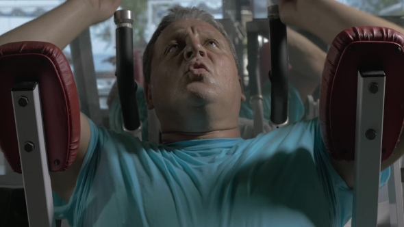 Grown Man In Blue Shirt In The Gym Performing Exercises On The Upper Abs