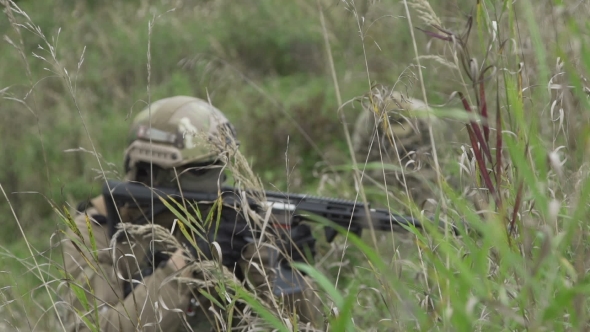 Soldiers Sitting In Wait In The Grass. Military In Arms Over The Hill