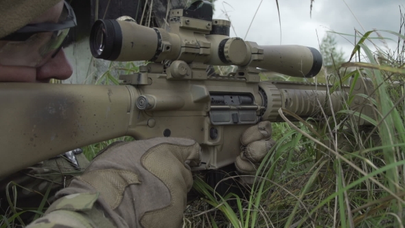 Sniper Lies Behind Cover In The Grass With a Gun In His Hand And Shoots
