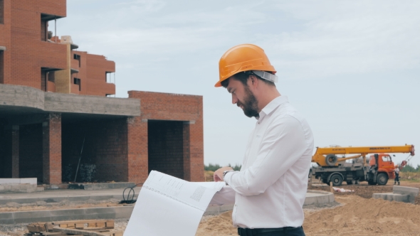 Engineer With Blueprint At Construction Site