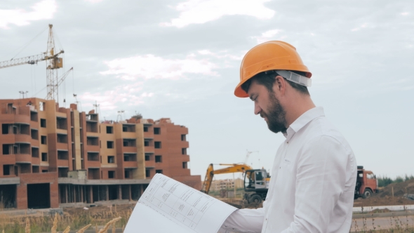 Engineer With Blueprint At Construction Site