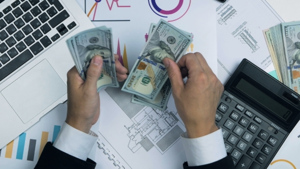 Businessman Counting Money. Accountant Workplace With Laptop, Graphs, Calculator.