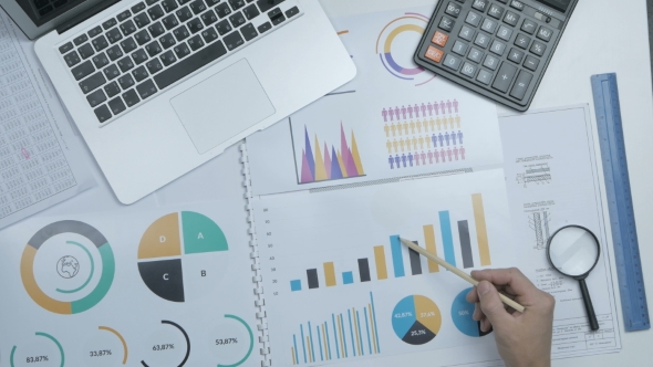 Businessman Working At Office Desk On His Laptop And Financial Reports