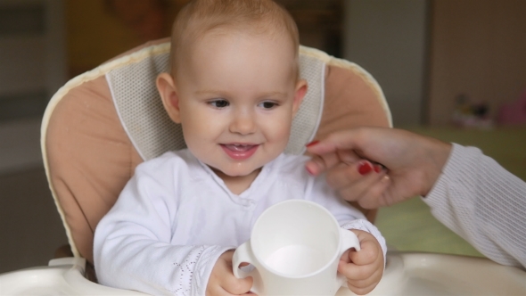 Little Girl Drink Water In Child Seat And Smiling. Happy Family Concept. Mother With Spoon And Baby