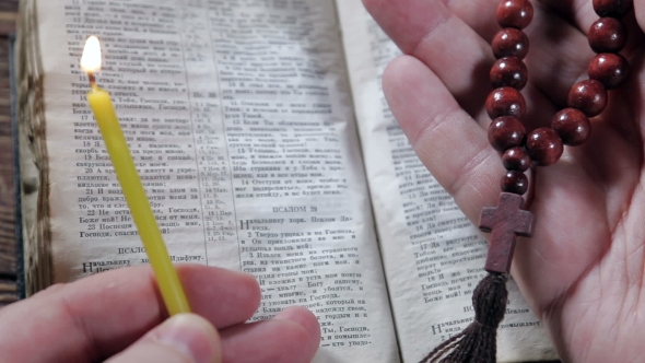 Hands Holding The Bible And Praying With a Rosary